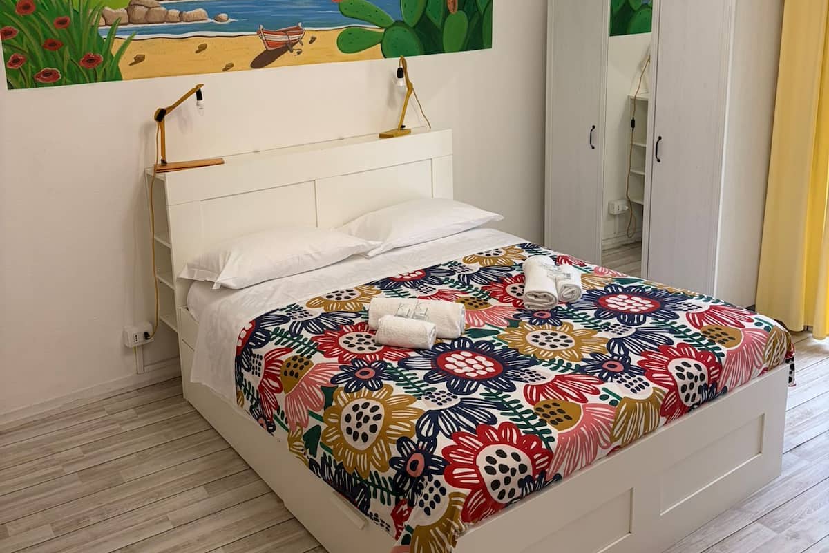 Une chambre à coucher avec un lit, un tableau, une armoire et un luminaire au plafond.