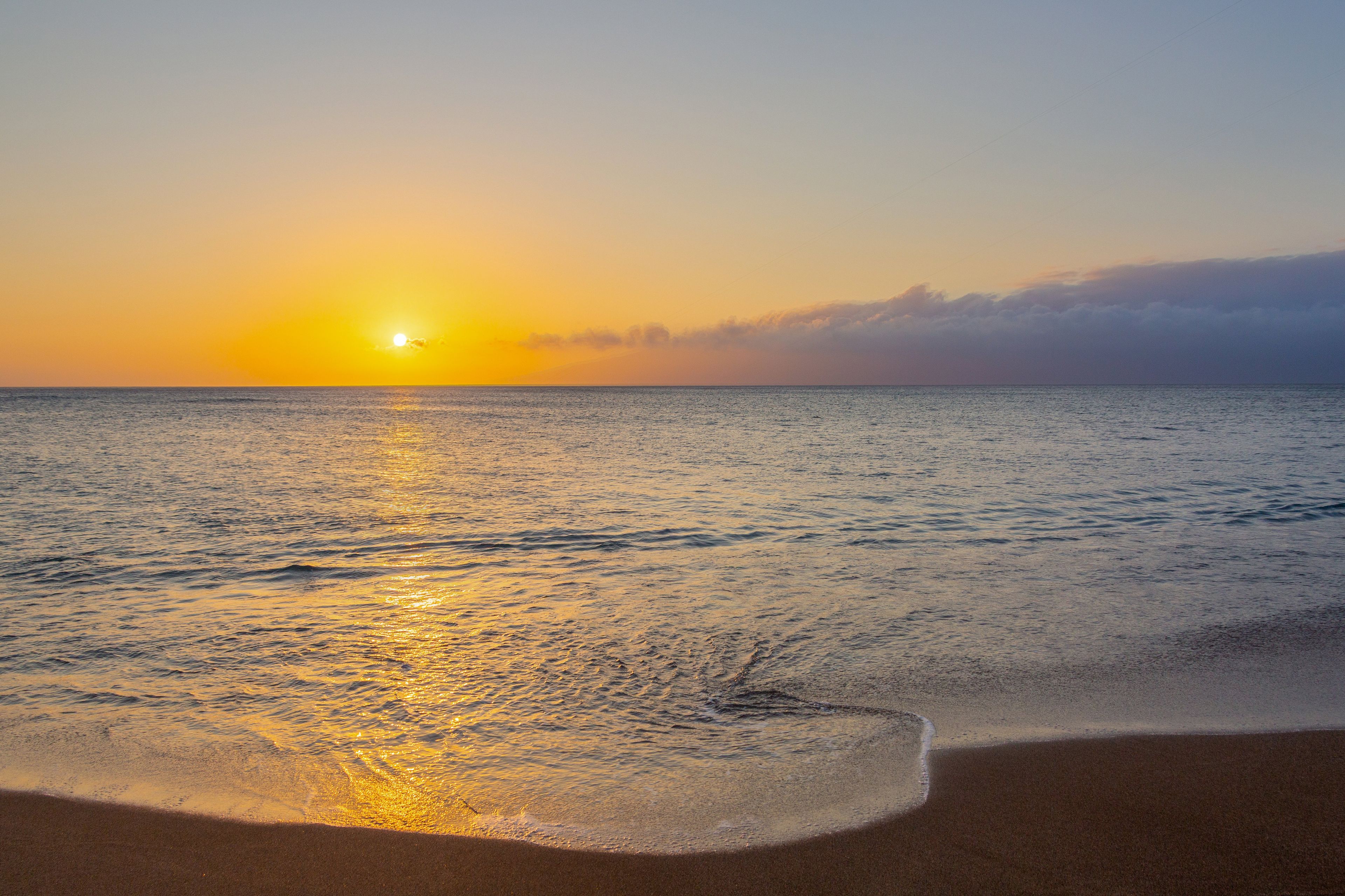 Una playa con un atardecer sobre el océano.