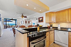 A modern kitchen with a central island, wooden cabinets, and a view to the outside. - Serenity framed by floor-to-ceiling Ocean views (Lahaina)