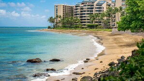 A beachfront hotel with multiple floors, palm trees, and a sandy beach. - Serenity framed by floor-to-ceiling Ocean views (Lahaina)