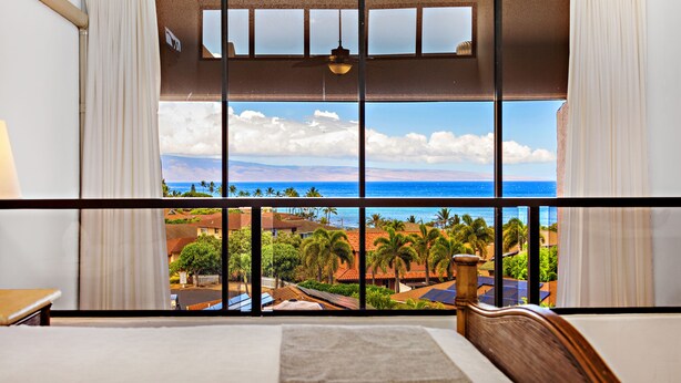 A hotel room with a large window offering a view of the ocean and palm trees. - Serenity framed by floor-to-ceiling Ocean views (Lahaina)