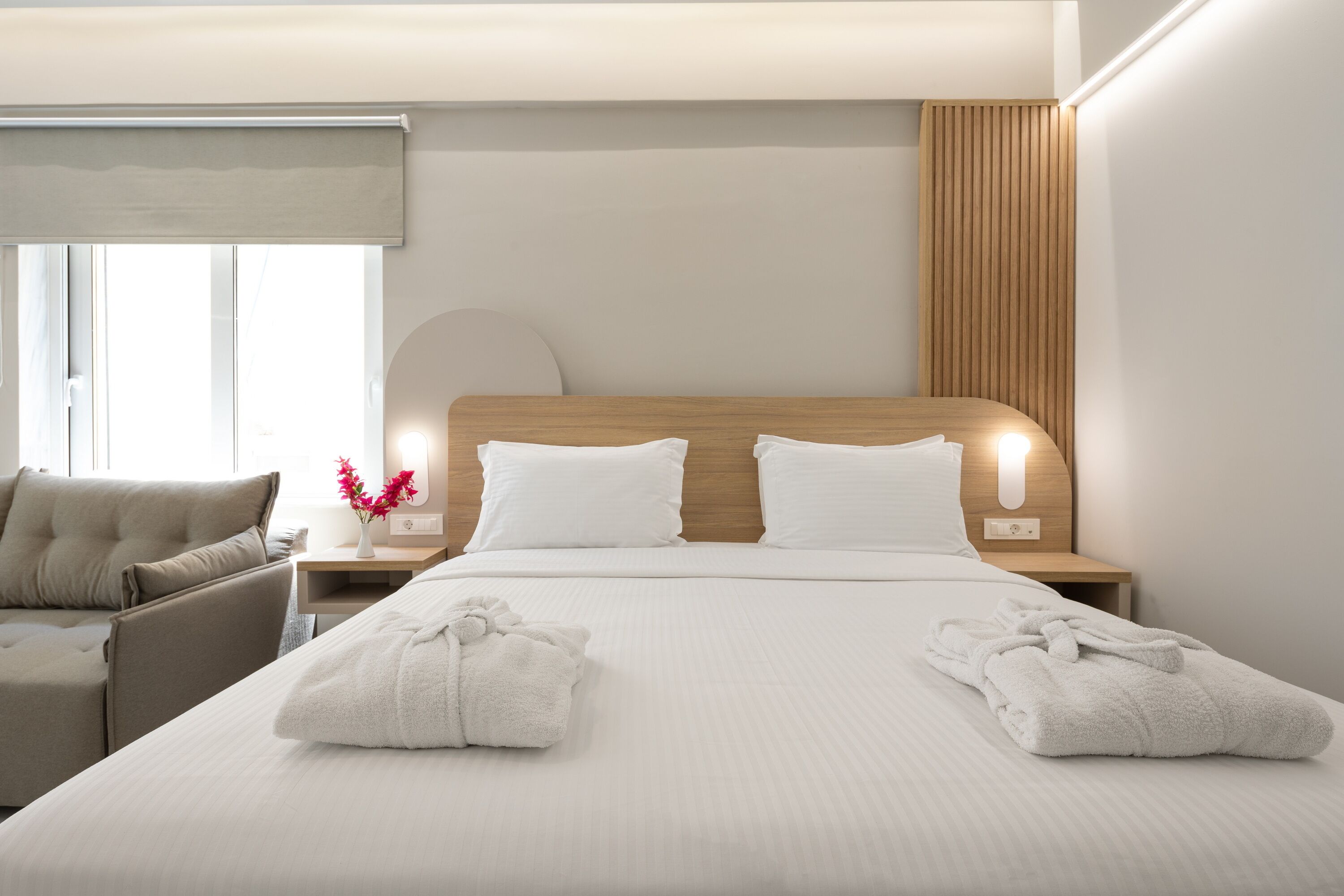 A hotel room with a large bed, a nightstand with a lamp, a chair, and a window with blinds.