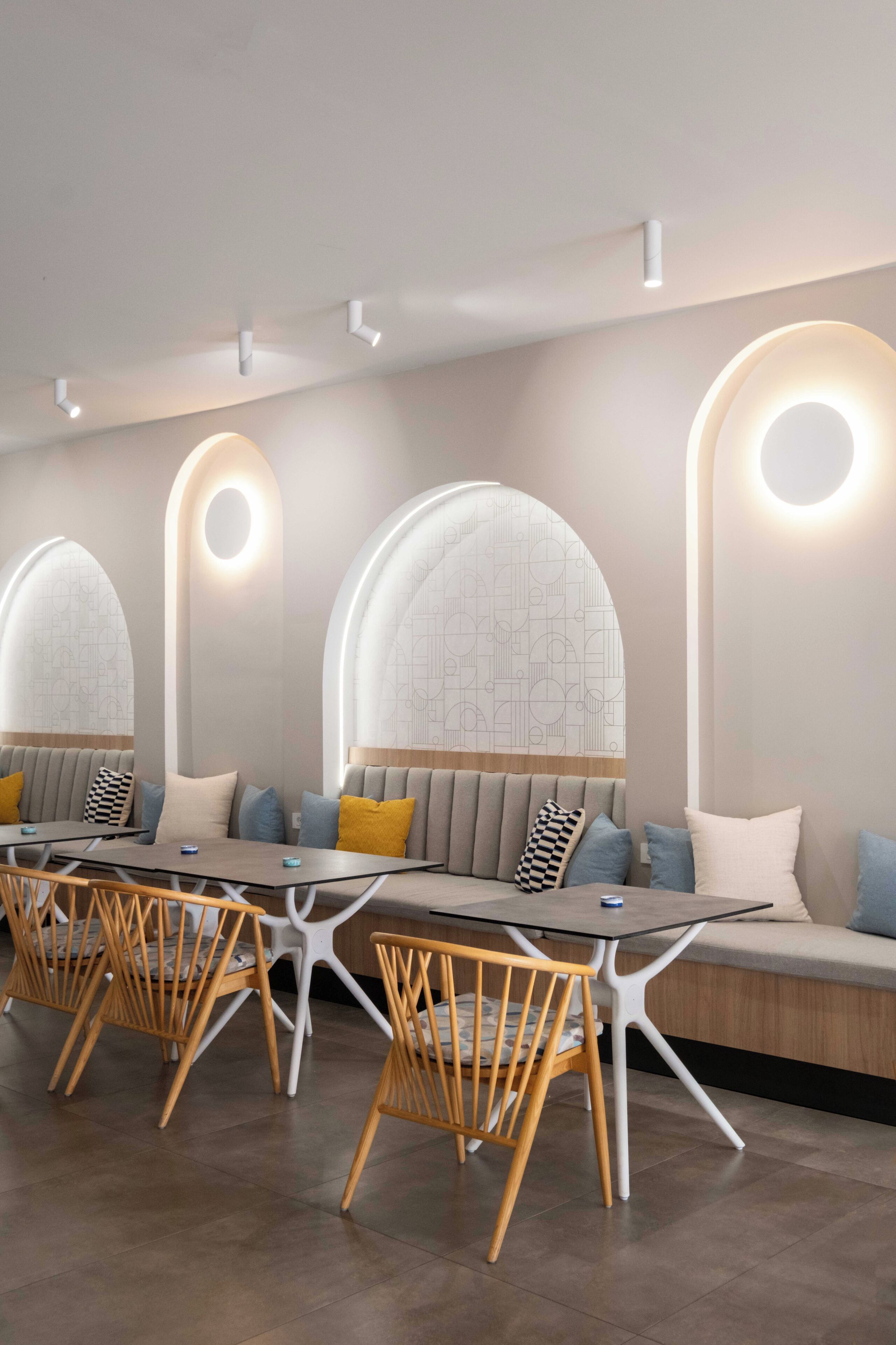 A modern dining area with a long table, white chairs, and cushioned seating.