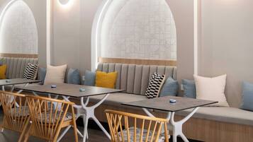 A modern dining area with a long table, white chairs, and cushioned seating.