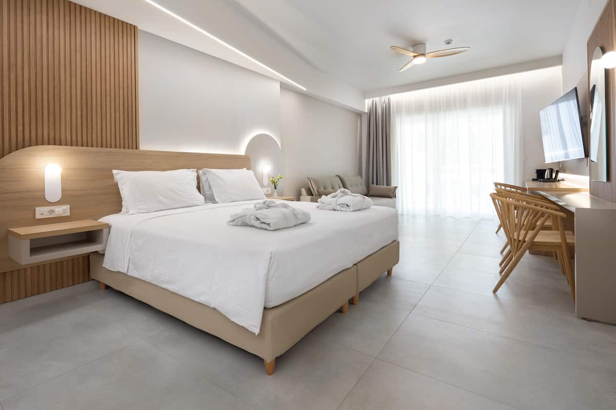 A modern hotel room with a large bed, bedside tables, a desk, and a television.