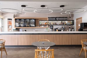 Un área de bar moderna con mostrador, asientos y una máquina de café.