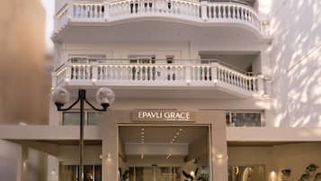 Een hotel met meerdere verdiepingen, een witte gevel, balkons en een bordje waarop 'EPAVLI GRACE' staat.