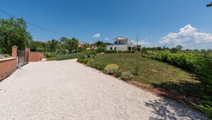 A residential property with a gravel driveway, a well-maintained lawn, and a house with a stone facade. - Tola in Vi Njan With 3 Bedrooms and 3 Bathrooms (Visnjan)