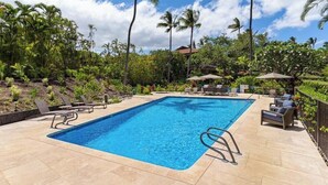 A rectangular swimming pool with a clear blue water surface, surrounded by lounge chairs and umbrellas, set against a backdrop of palm trees and tropical vegetation. - 
Premium Oceanfront Makena Surf #F-102 with Central AC & Island Views (Makena, Maui)