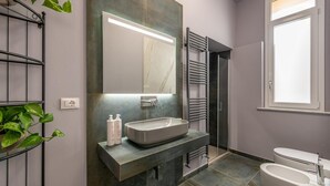 A modern bathroom with a large mirror, a built-in sink, and a separate toilet.