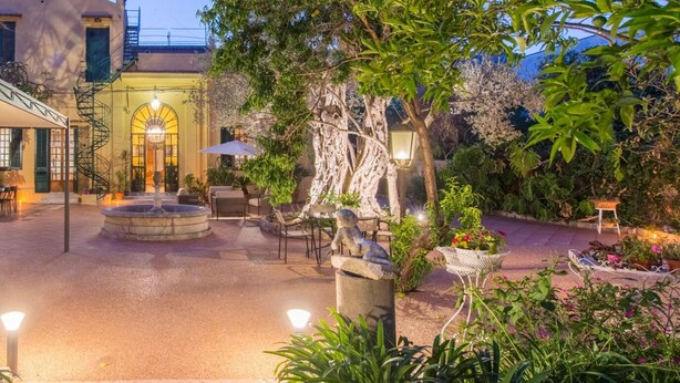 An outdoor courtyard with a fountain, seating area, and a building with a staircase.