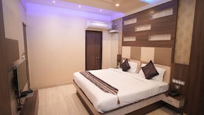 A modern hotel room with a large bed, a flat-screen TV, an air conditioning unit, and a bedside telephone. - Hotel Raj Kamal Palace (Varanasi)