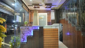 A reception desk with a glass partition, a wooden panel, and a ceiling fan. - Hotel Raj Kamal Palace (Varanasi)
