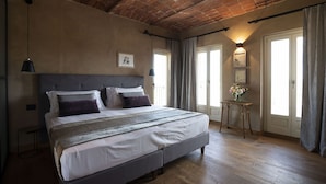 Ein Schlafzimmer mit einem großen Bett, einem Kopfteil, einem Nachttisch mit einer Vase und einer Ziegeldecken.
