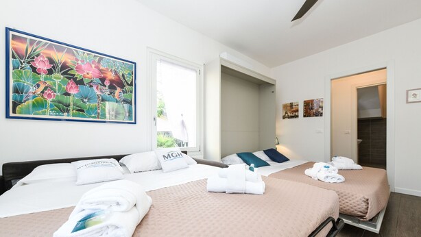 A hotel room with two beds, a large floral painting, and a view of the outdoors.