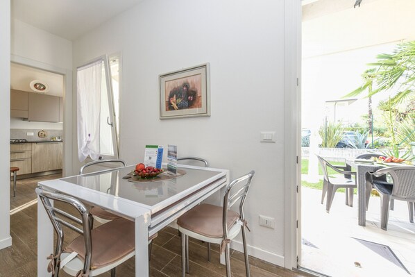 Un comedor con mesa de vidrio, sillas de metal y un cuadro en la pared.