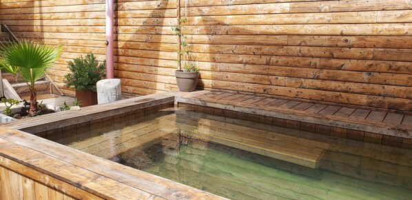 A wooden deck with a hot spring pool, surrounded by potted plants and a wooden wall. - Duplex Avec Jardin, Piscine, Terrasse, 3 Chambres (Palavas-les-Flots)