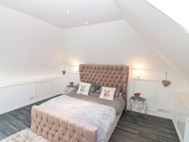A bedroom with a large bed, two bedside tables, a decorative wall hanging, and a sloped ceiling.