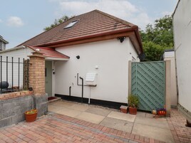 A house with a red roof, a green gate, and a small garden with potted plants.