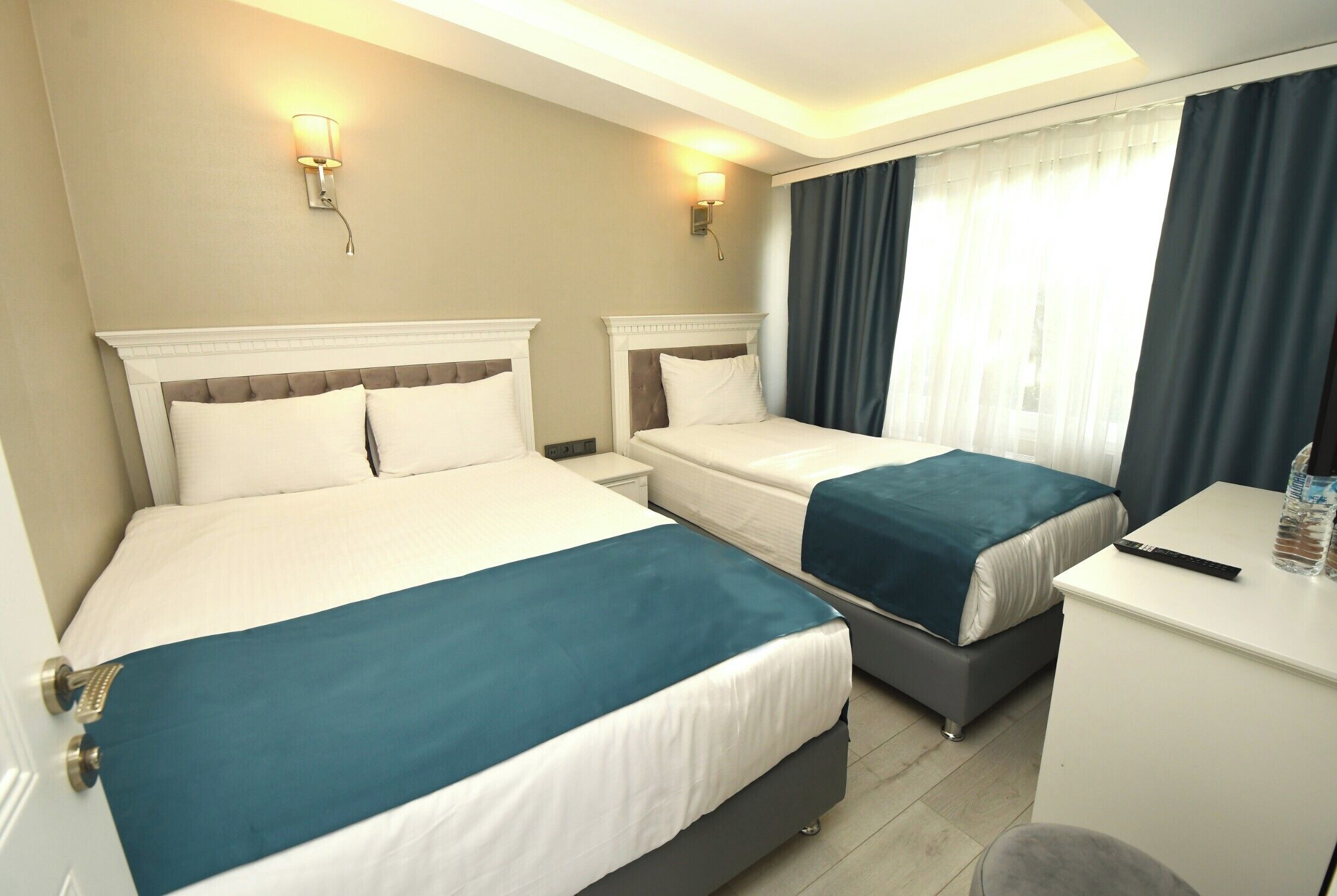 A hotel room with two beds, a desk, and a chair.