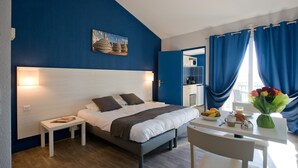 A modern bedroom with a bed, bedside table, and a small dining area with a table, chair, and breakfast items. - SOWELL RESIDENCES Les Hameaux (Arles)