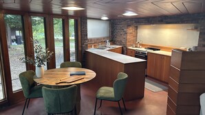 Una cucina moderna con isola centrale, mobili in legno e zona pranzo con tavolo rotondo e sedie.