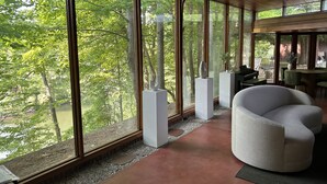 Un interno moderno con ampie finestre, una poltrona bianca dalla forma sinuosa e un pianoforte.