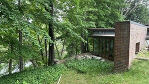 Un edificio moderno con ampie vetrate, circondato da una vegetazione lussureggiante e alberi.