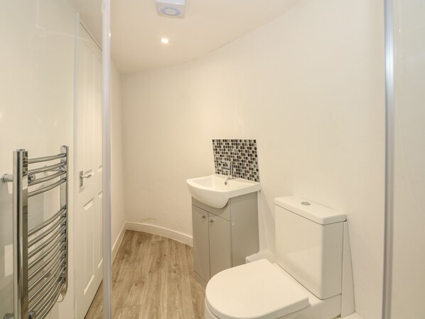 A small, clean bathroom with a white toilet, a sink with a mosaic backsplash, and a towel rack.