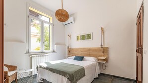 Une chambre à coucher comprenant un lit, une fenêtre, un radiateur, une lampe suspendue et une étagère fixée au mur.