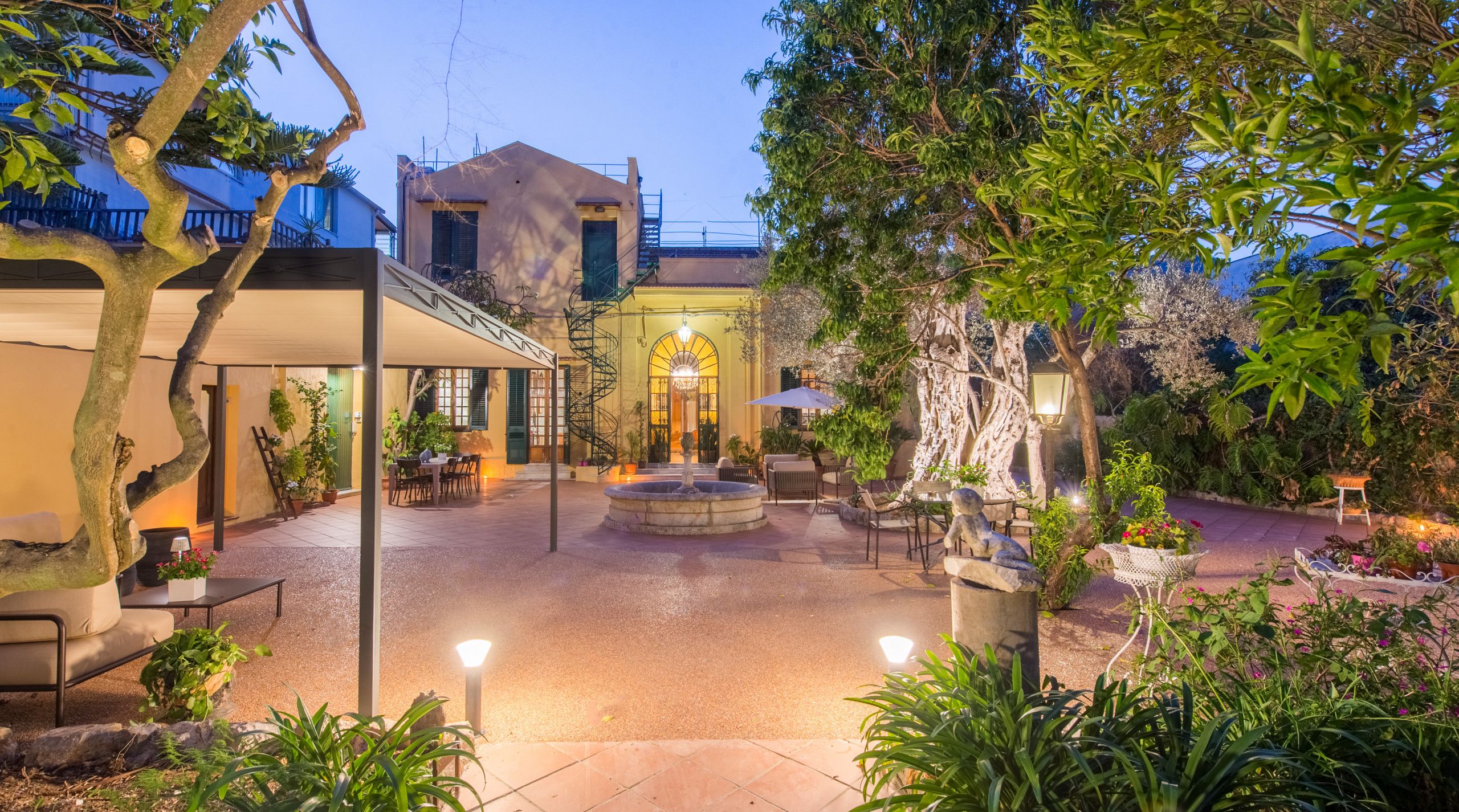 Un patio con una fuente, asientos exteriores y un edificio con una escalera.