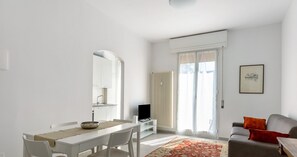 Ein modernes Wohnzimmer mit Essbereich, einer Couch und einem Fernseher.