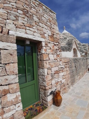 A stone building with a green door and a small window. - The Flower of Life Trulli Country house (Conversano)