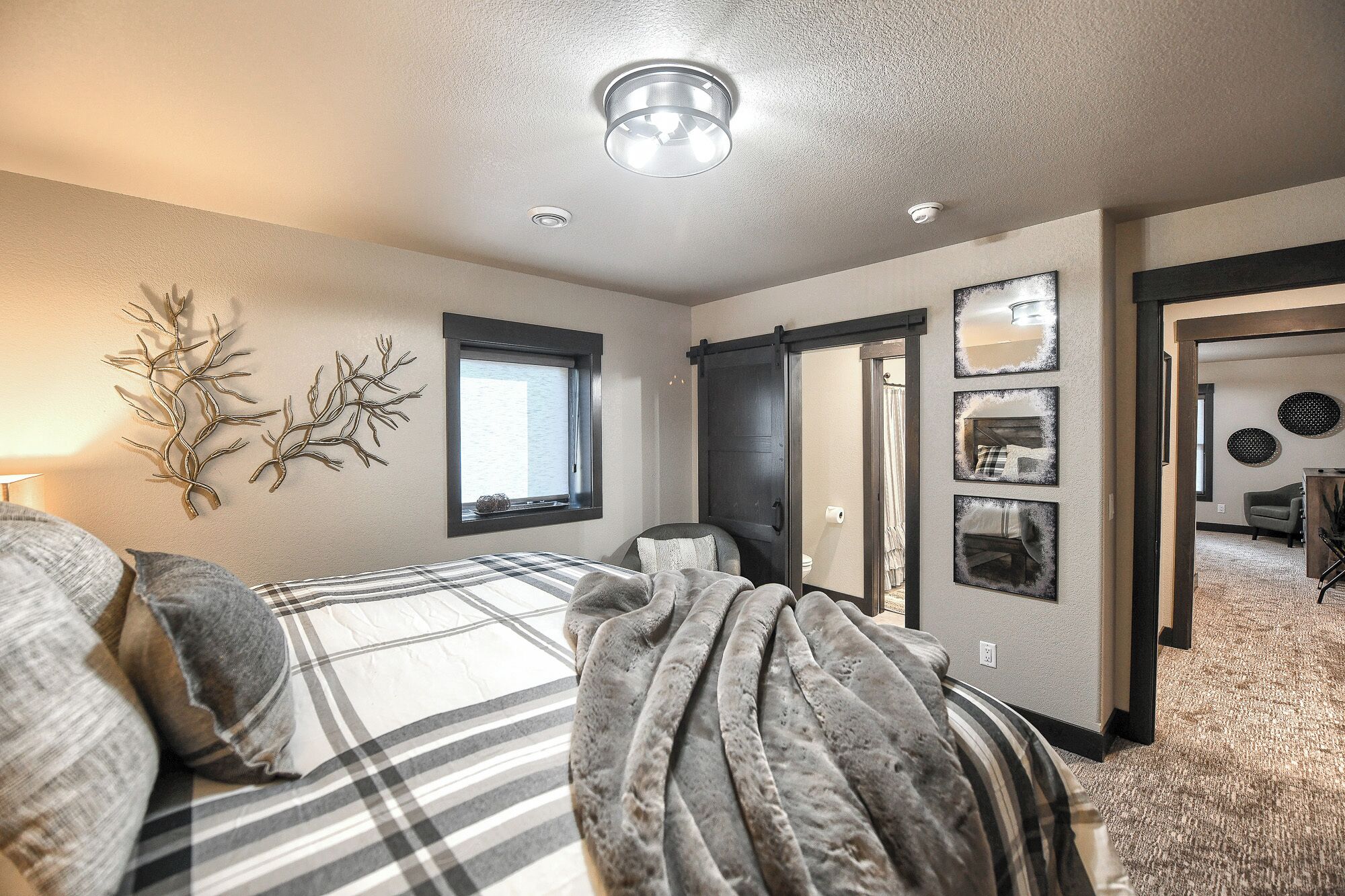 A bedroom with a bed, a window, and a door leading to another room.