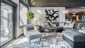 A modern living room with a grey sofa set, a round coffee table, and a large abstract painting on the wall. - Open Floor Plan, Walking Distance to Clubhouse, 4400+ Sq. Ft. Large Driveway! (Lead)