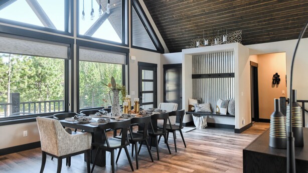 A modern dining area with a large table and chairs, large windows with a view of trees, and a dark wooden ceiling. - Open Floor Plan, Walking Distance to Clubhouse, 4400+ Sq. Ft. Large Driveway! (Lead)
