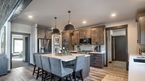 A modern kitchen with a central island, dark wooden cabinets, stainless steel appliances, and pendant lighting. - Open Floor Plan, Walking Distance to Clubhouse, 4400+ Sq. Ft. Large Driveway! (Lead)