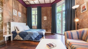 A bedroom with a bed, a sofa, a bedside table, a lamp, and a window with curtains. - The Green Bar House (Sofia)