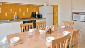 A kitchen with a dining table set for four, equipped with chairs, a coffee maker, a refrigerator, and a microwave. - Large family home with garden- For 10 (Penmarch)