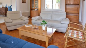 A living room with a beige sofa, a blue sofa, a wooden coffee table, and a wicker chair. - Large family home with garden- For 10 (Penmarch)