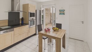 Eine moderne Küche mit Holzschränken, Edelstahlgeräten und einem Essbereich mit Tisch und Stühlen.