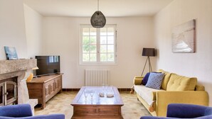 Una sala de estar con chimenea, televisor, mesa de centro con vasos, sofá y lámpara.