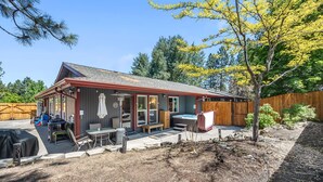 Een klein huisje met een terras, buitenmeubels en een jacuzzi.
