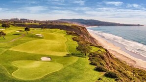 Un parcours de golf situé sur la côte, avec une plage de sable et une vue sur l’océan.