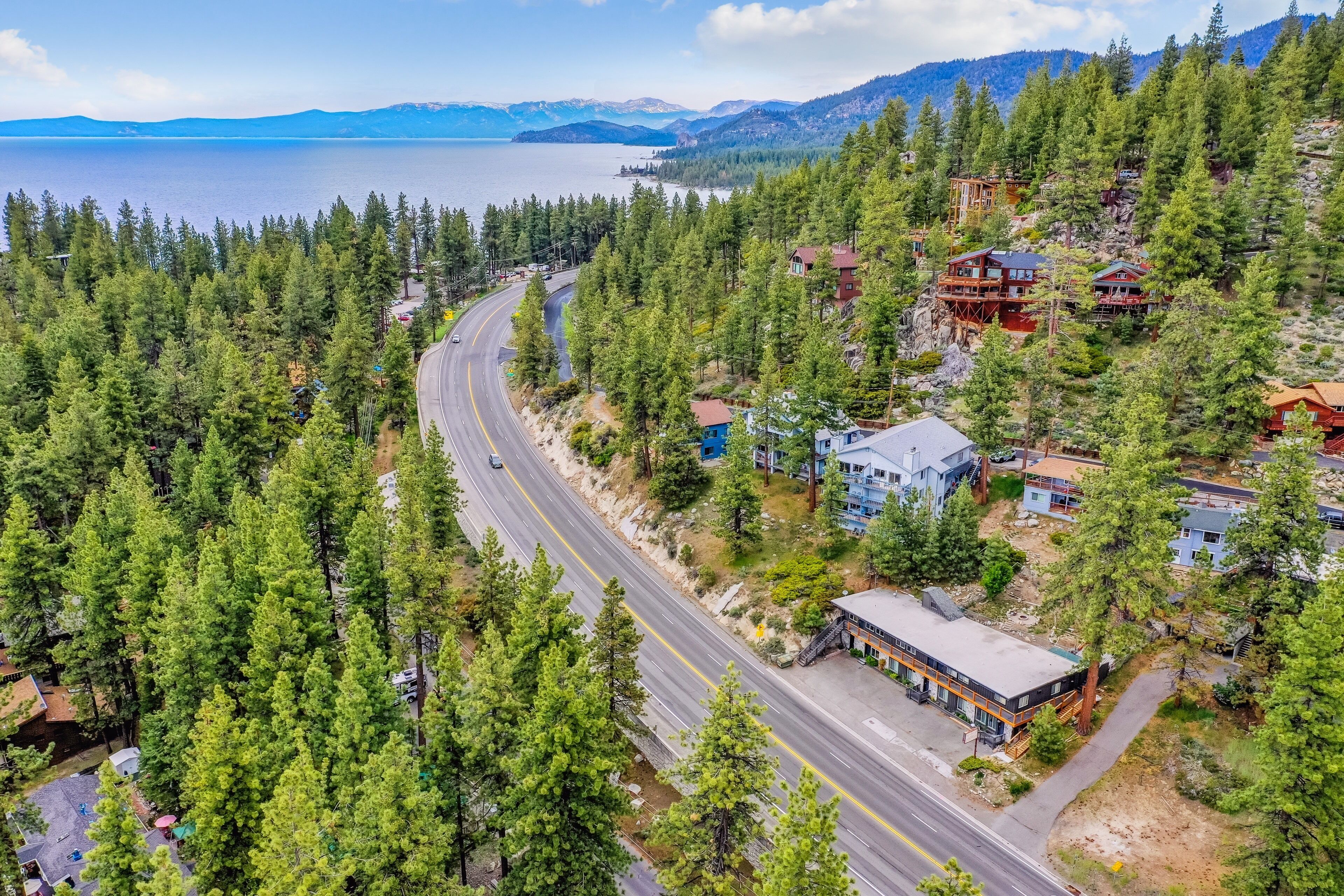A mountainous area with a road, buildings, and dense forest.