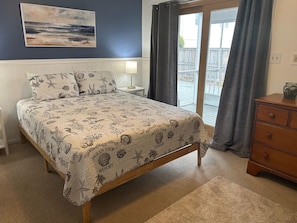 Quarto com cama, mesa de cabeceira, cômoda, janela com cortinas e um quadro na parede.