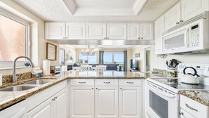 A modern kitchen with white cabinetry, granite countertops, and stainless steel appliances.