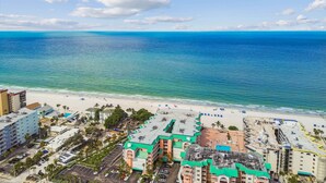A coastal hotel with multiple buildings, a beach, and a clear view of the ocean.