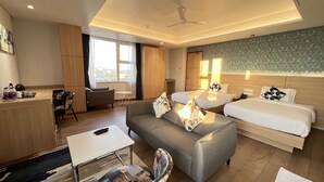 A hotel room with two beds, a sofa, a small table, and a desk with a chair. - Aurora Boutique Hotel (Imphal)