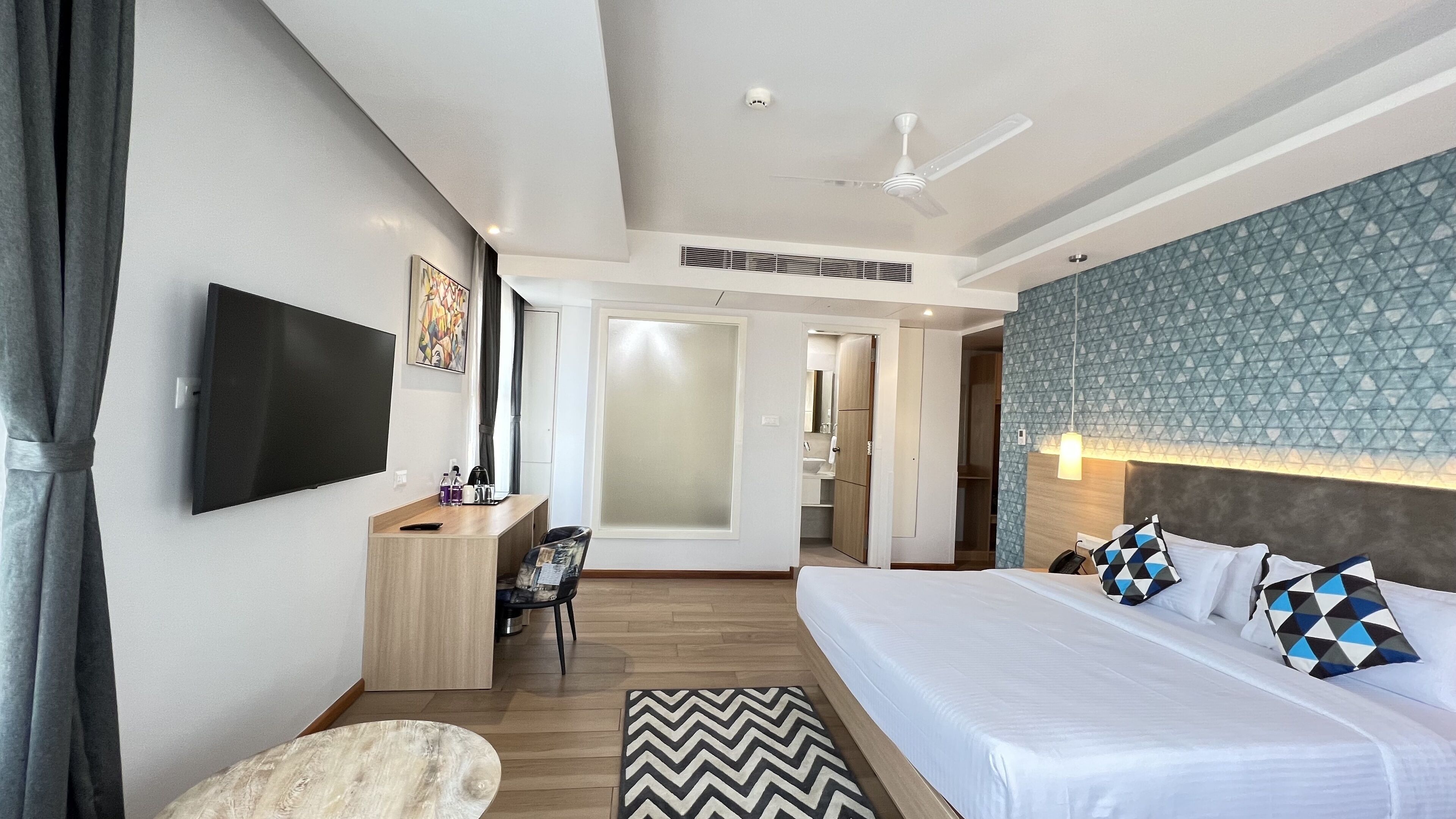 Una habitación de hotel moderna con una cama grande, un escritorio, un televisor de pantalla plana y un vestidor.